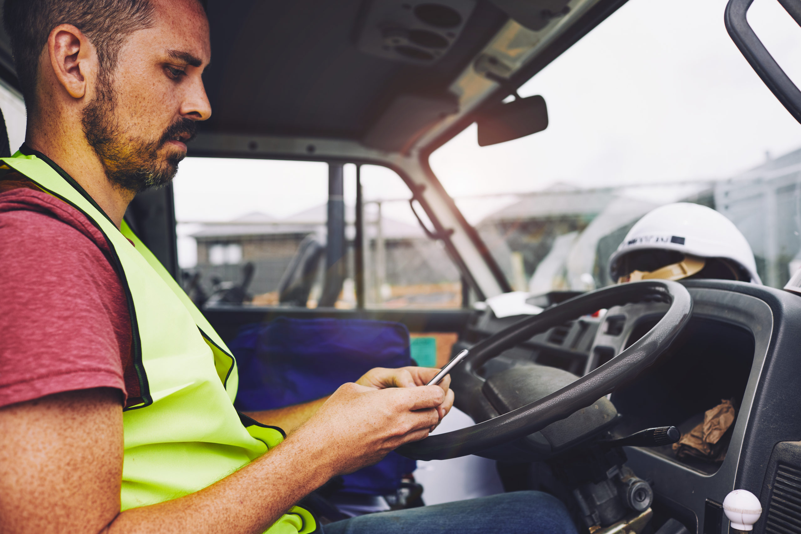 Construction industry worker texting on the phone inside a truck. Fleet Management & Business Software