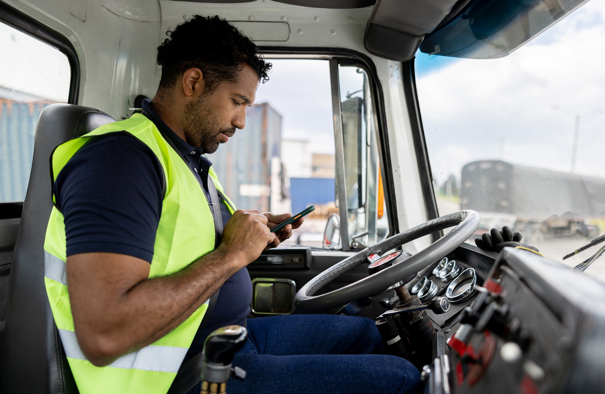 Truck driver transporting merchandise and using a GPS system on his cell phone Fleet Management & Business Software